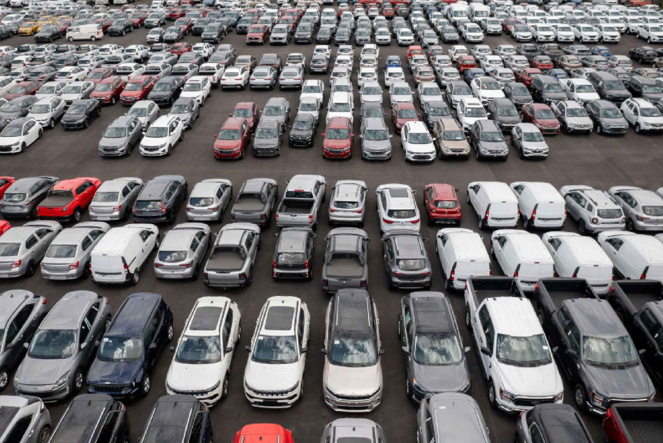 Parking lot of used cars for sale in a dealership on an overcast day.