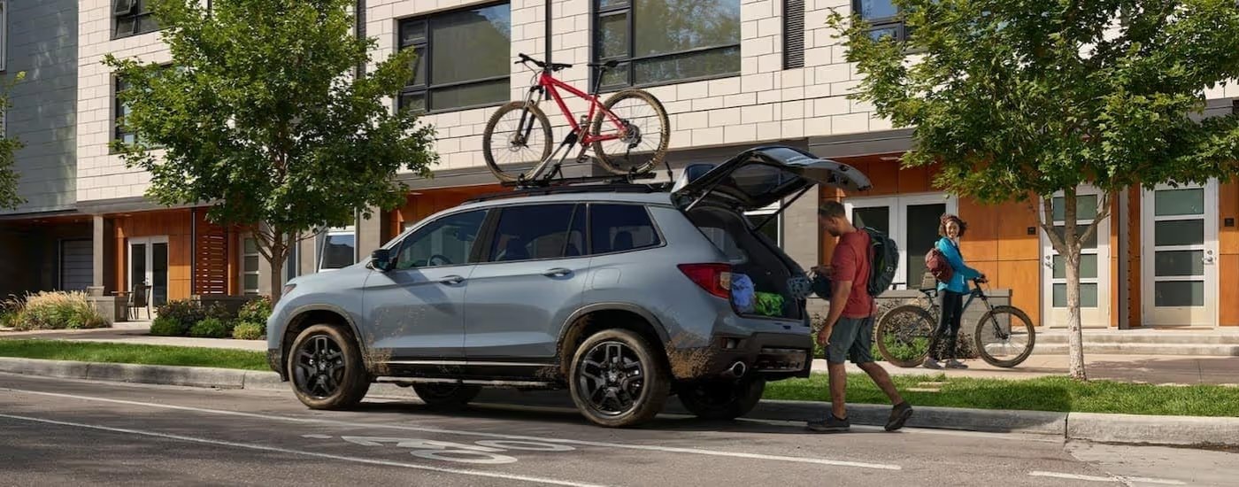 Bikers near a gray 2024 Honda Passport Black Edition