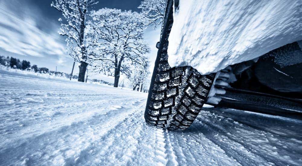 A car is shown from a low angle while driving on a snowy road.