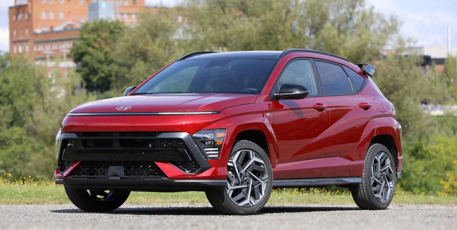 2024 Hyundai Kona parked outdoors showcasing its sleek and sporty design in a vibrant red color.