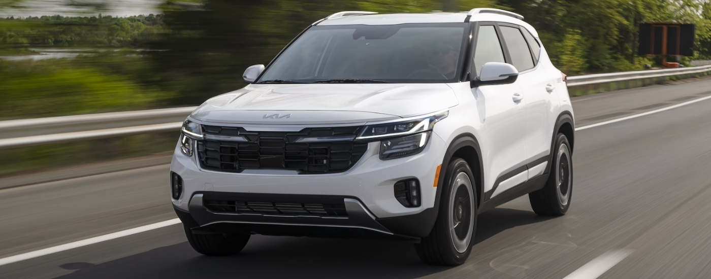 White 2025 Kia Seltos driving to a Kia dealer near Bloomington