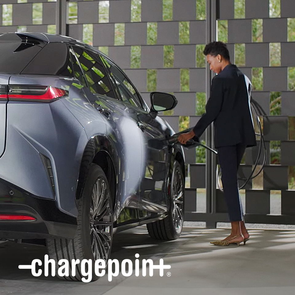 A person plugs a charger into their vehicle's charging port. 