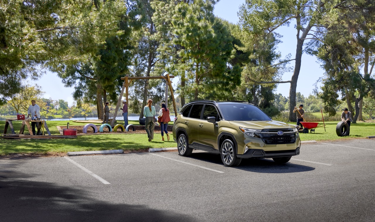 A Subaru Forester Hybrid parked in a sunny park lot near a playground.