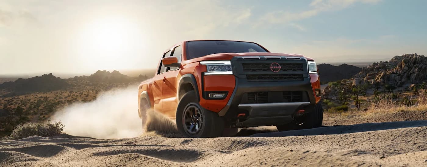 Orange 2026 Nissan Frontier driving off-road.