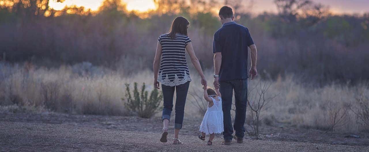 Family walking hand in hand on a trail at sunset