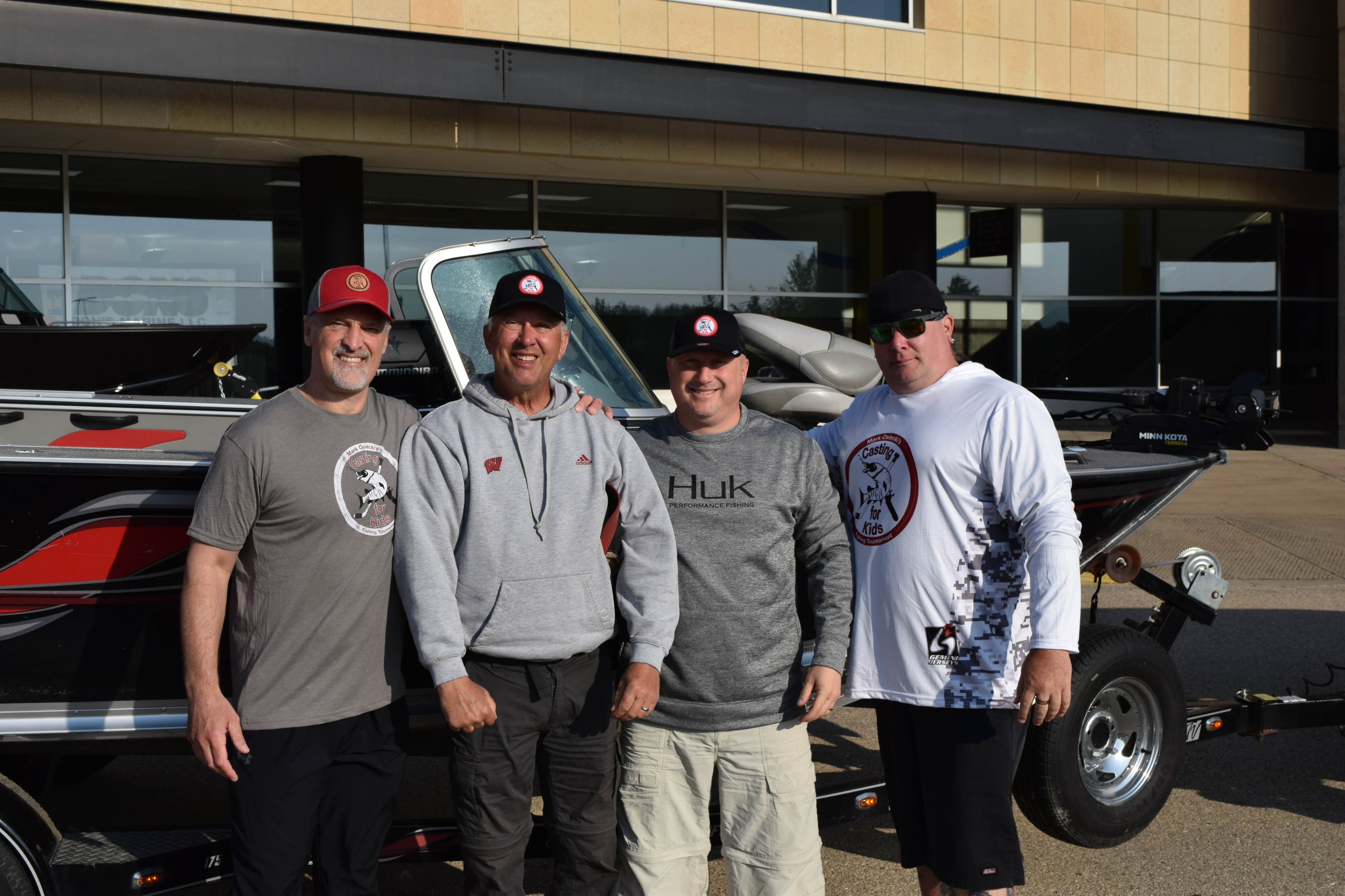 Michael Whitefeather, pictured on far right, poses in front of his boat with 3 other volunteers at Casting for Kids event