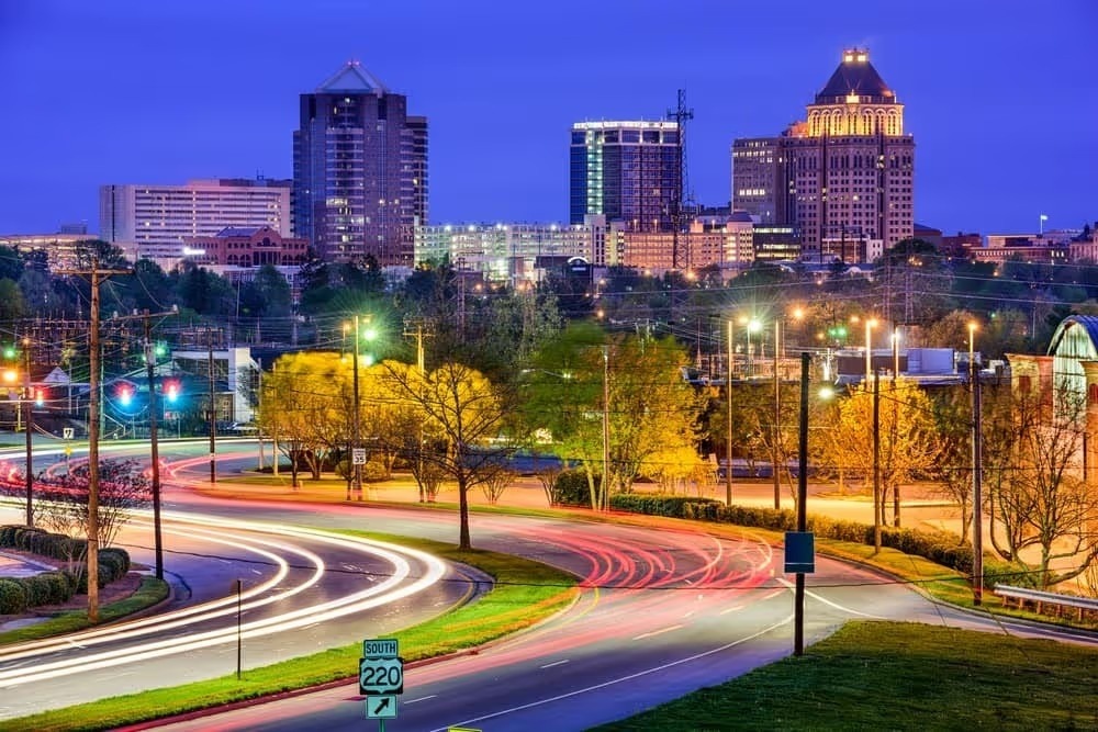 Greensboro skyline at dusk with light trails on the highway