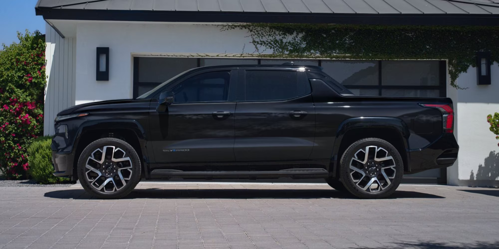 A black truck sitting parked in a driveway.