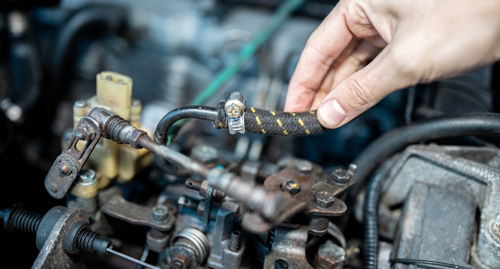 Hand inspecting a vehicle hose for wear or damage.