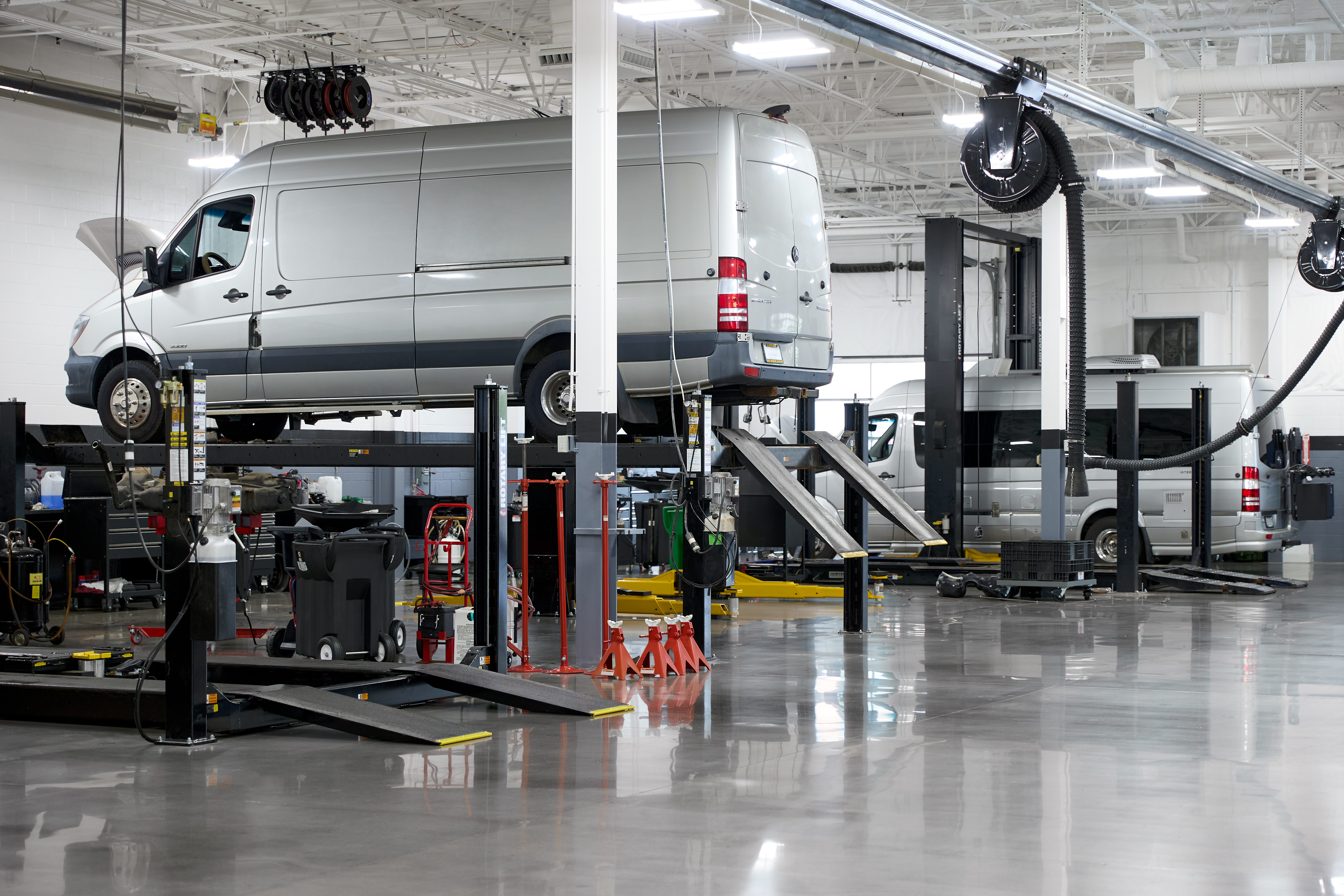 A Mercedes-Benz Sprinter van on a lift in a service bay