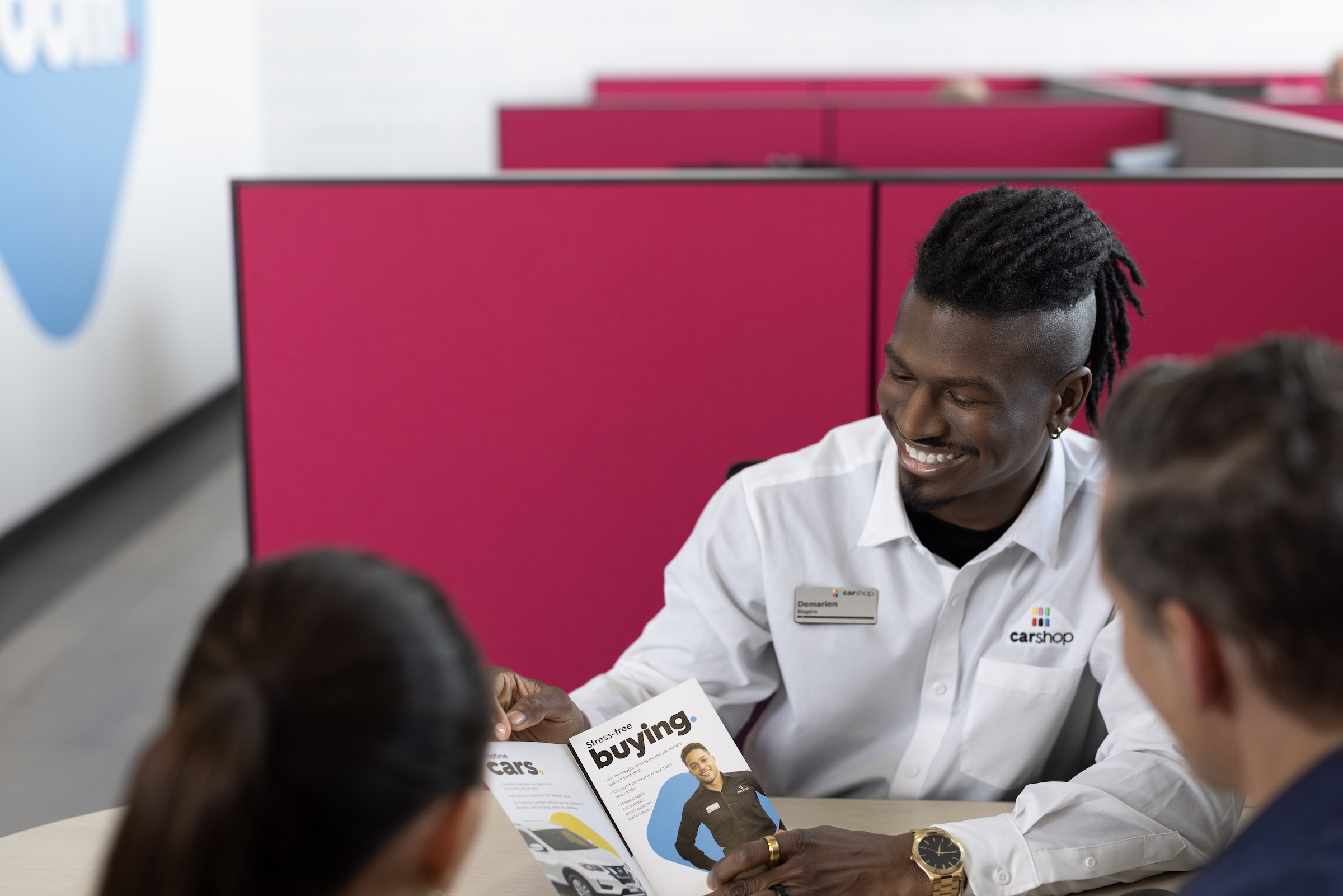 Associate showing two customers Carshop brochure