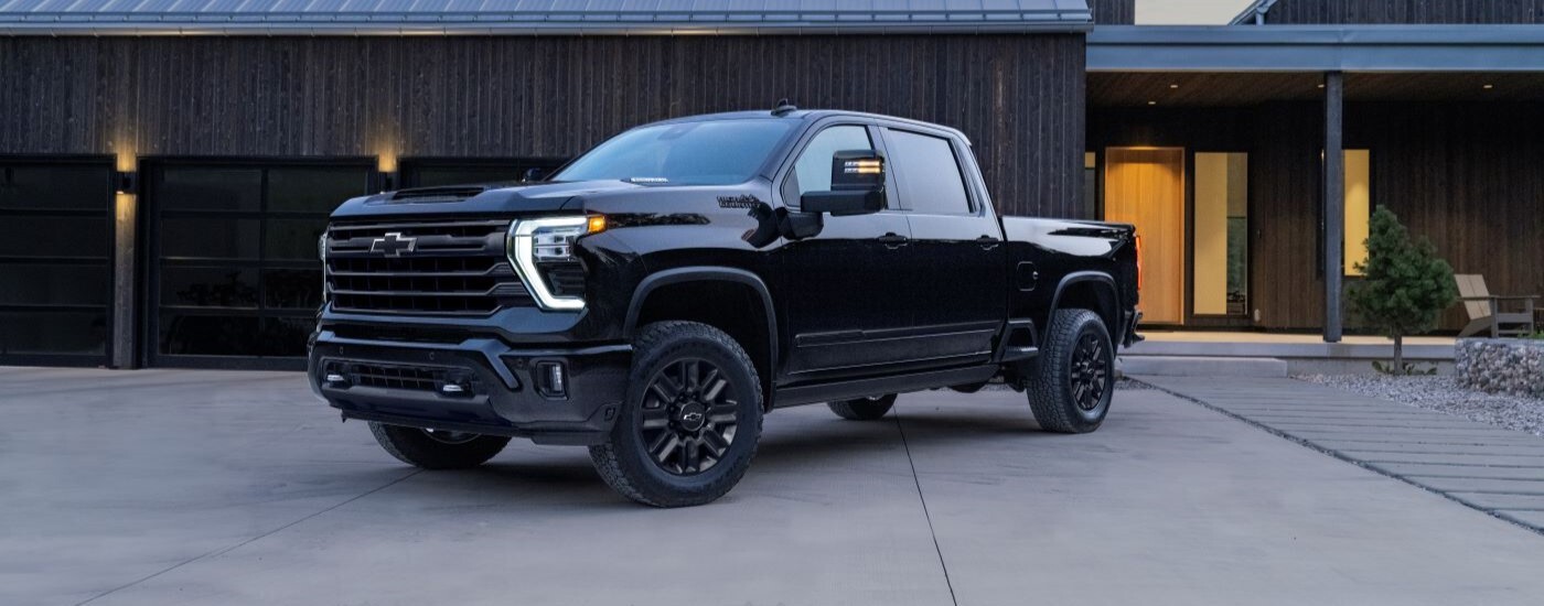 Black 2024 Chevy Silverado 2500 HD High Country parked in front of a house.