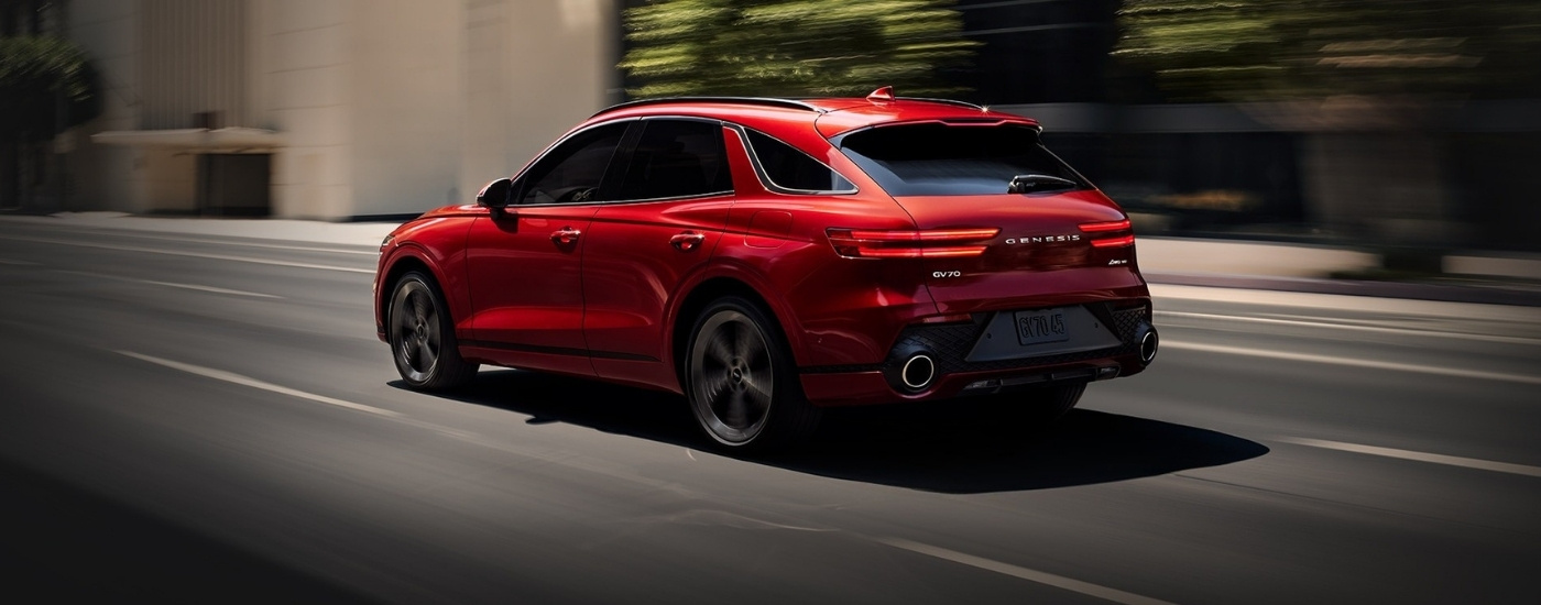 Red 2022 Genesis GV70 driving on a city street