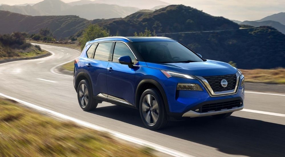 Blue 2021 Nissan Rogue on a winding road