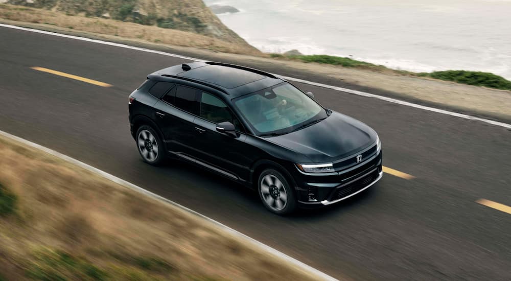 Black 2026 Honda Prologue driving on a highway near an ocean