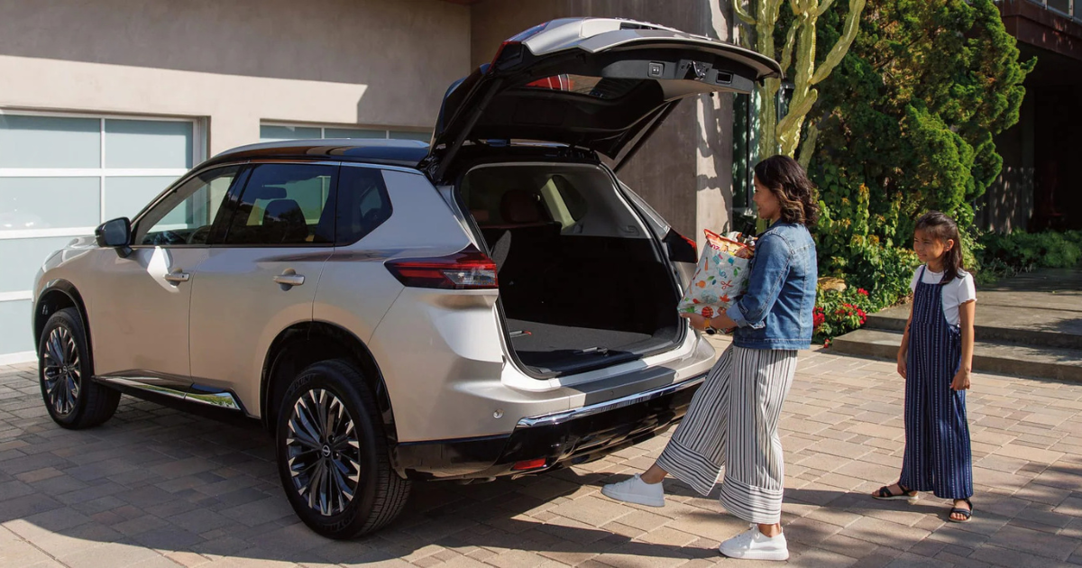 Nissan Rogue parked in a driveway with a family approaching to enter the vehicle