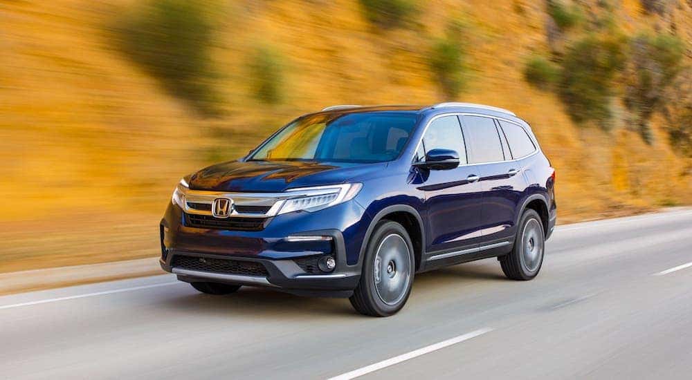 Blue 2020 Honda Pilot is driving on a road near Rochester, NY.