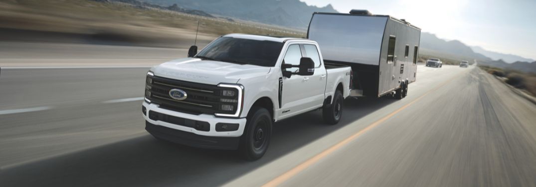 White 2025 Ford Super Duty Towing a Trailer on a Highway