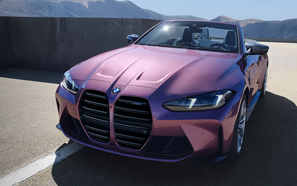 A pink BMW M4 Convertible sitting on the top floor of a parking garage