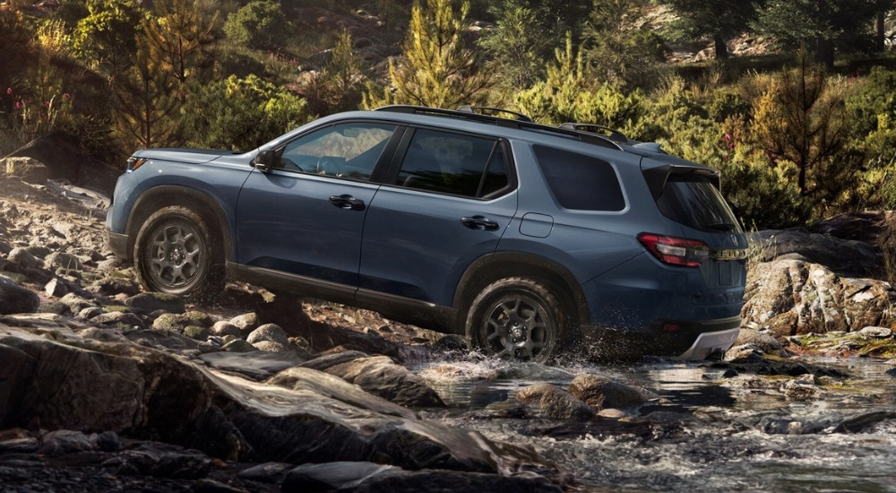 Dark blue 2026 Honda Pilot TrailSport driving off-road