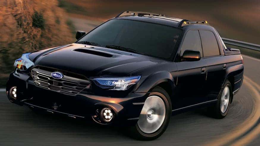 Black Subaru Baja pickup driving on a winding road
