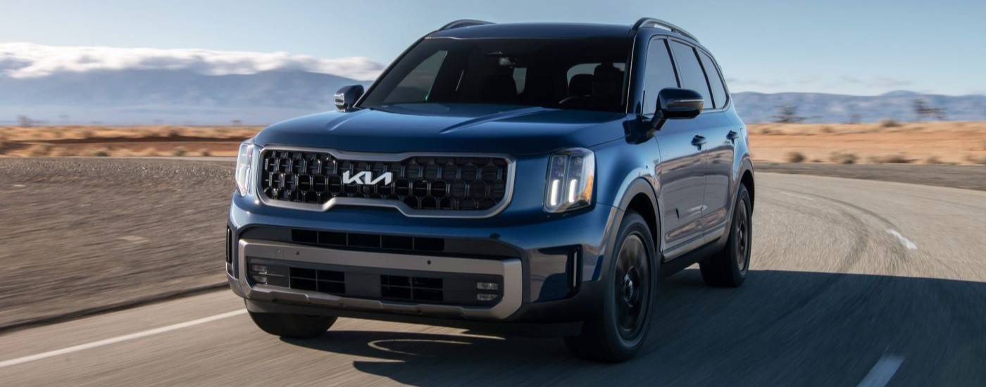 Blue 2023 Kia Telluride driving down a highway