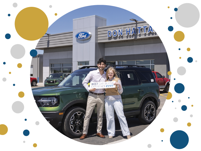 Couple at Don Hattan Ford holding a sign saying "Best car buying experience ever" while standing in front of a new Ford Bronco Sport.