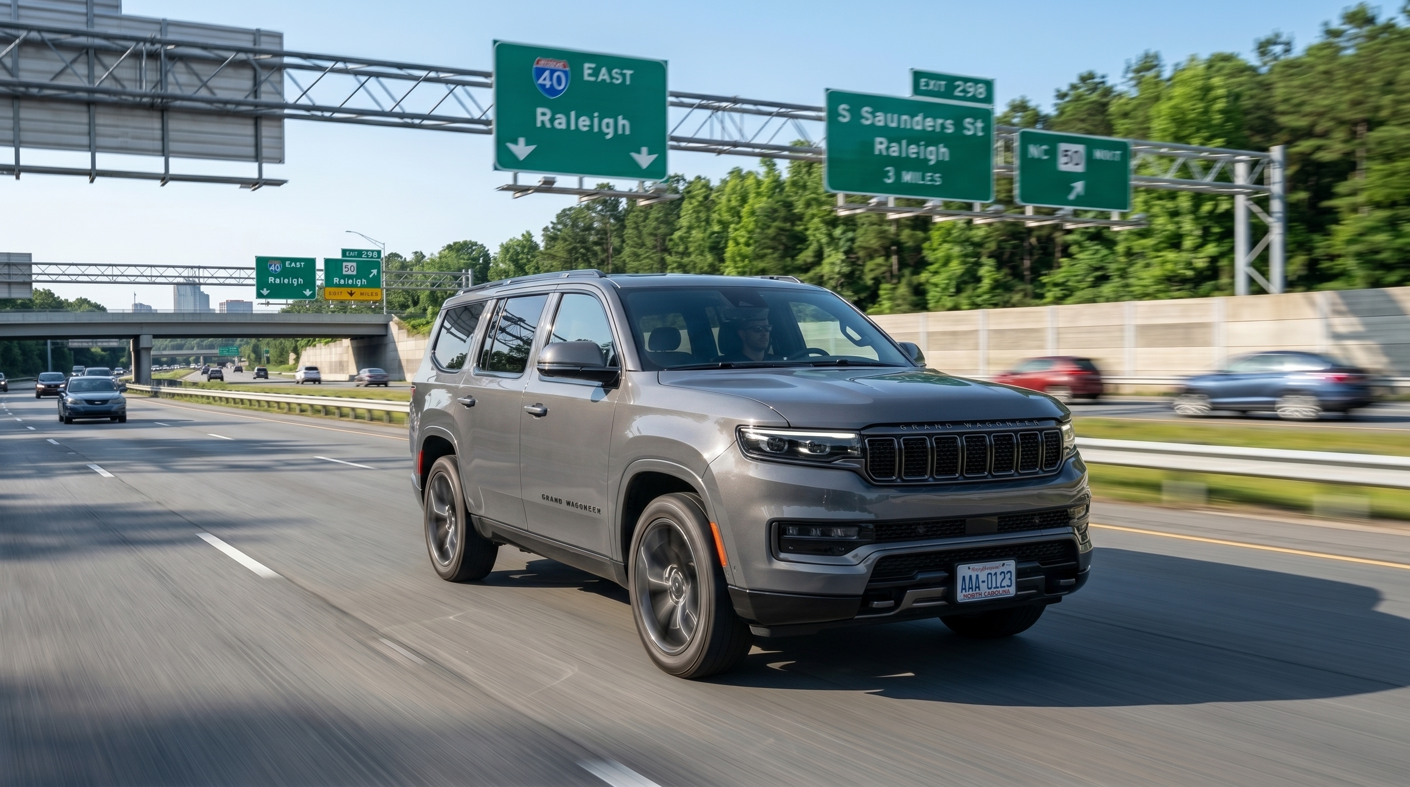 A gray Jeep Grand Cherokee L three-row SUV driving on Interstate 40 East near Exit 298 for South Saunders Street and NC 50 in Raleigh, showcasing its highway commuting style.