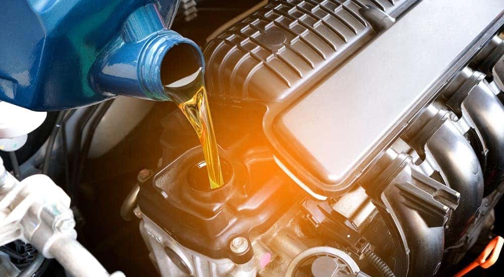 A canister of oil being poured into an engine during an oil change near Greece.