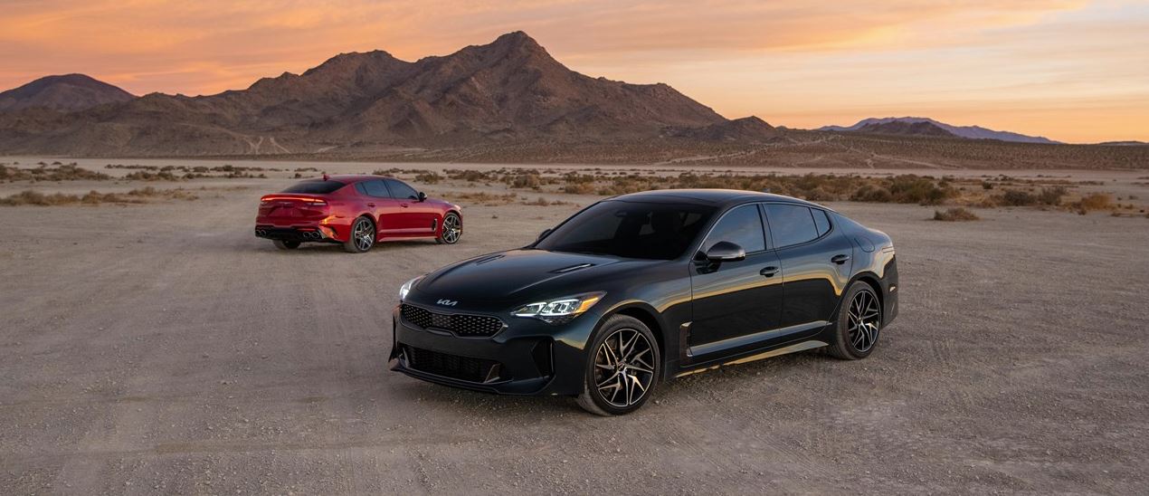 front pictured: black 2023 Kia Stinger; background pictured: red 2023 Kia Stinger pictured in a dessert