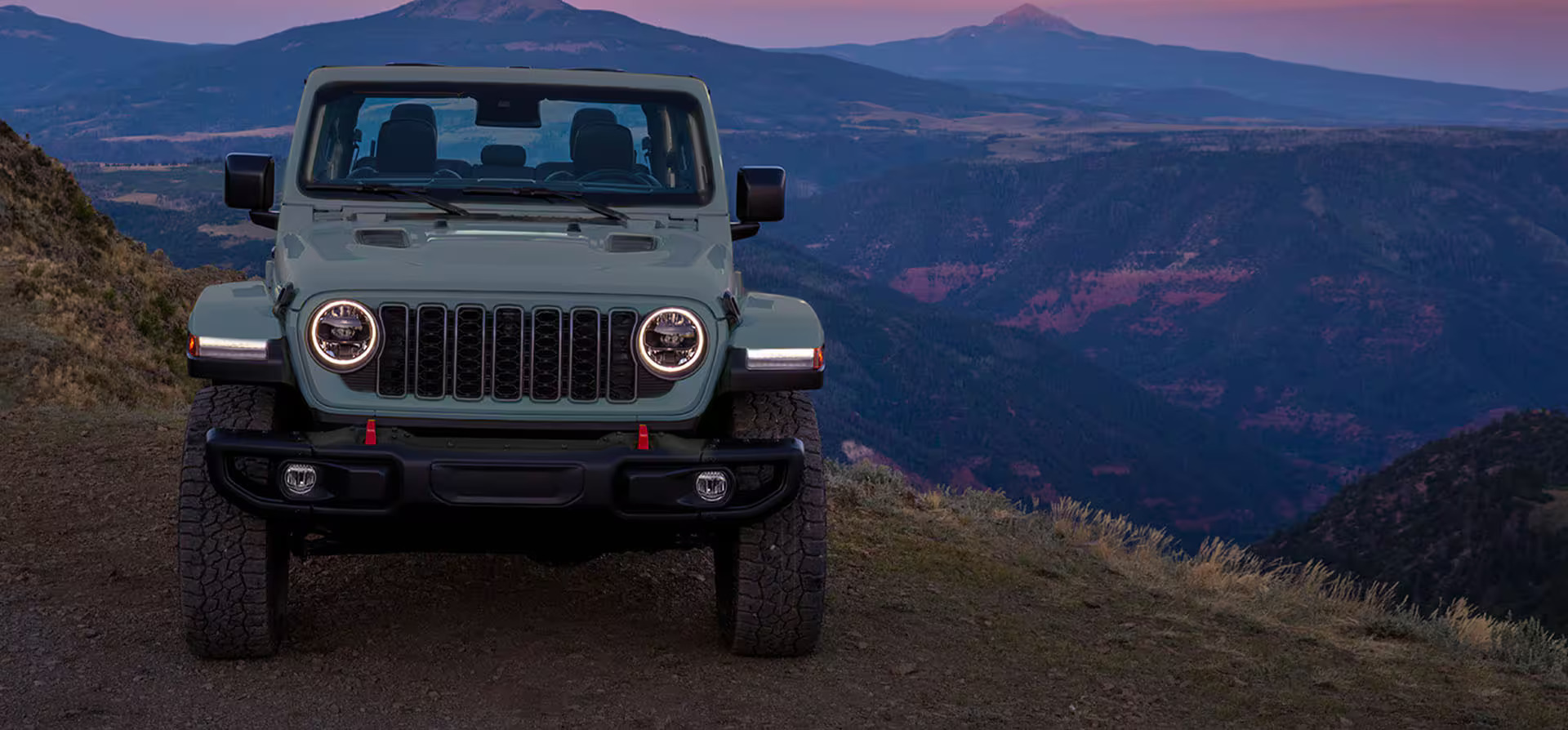 A blue jeep sitting parked on a hill.