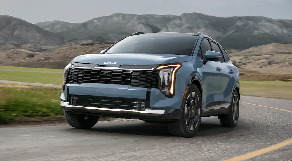 Blue 2026 Kia Sportage Hybrid driving around a bend.