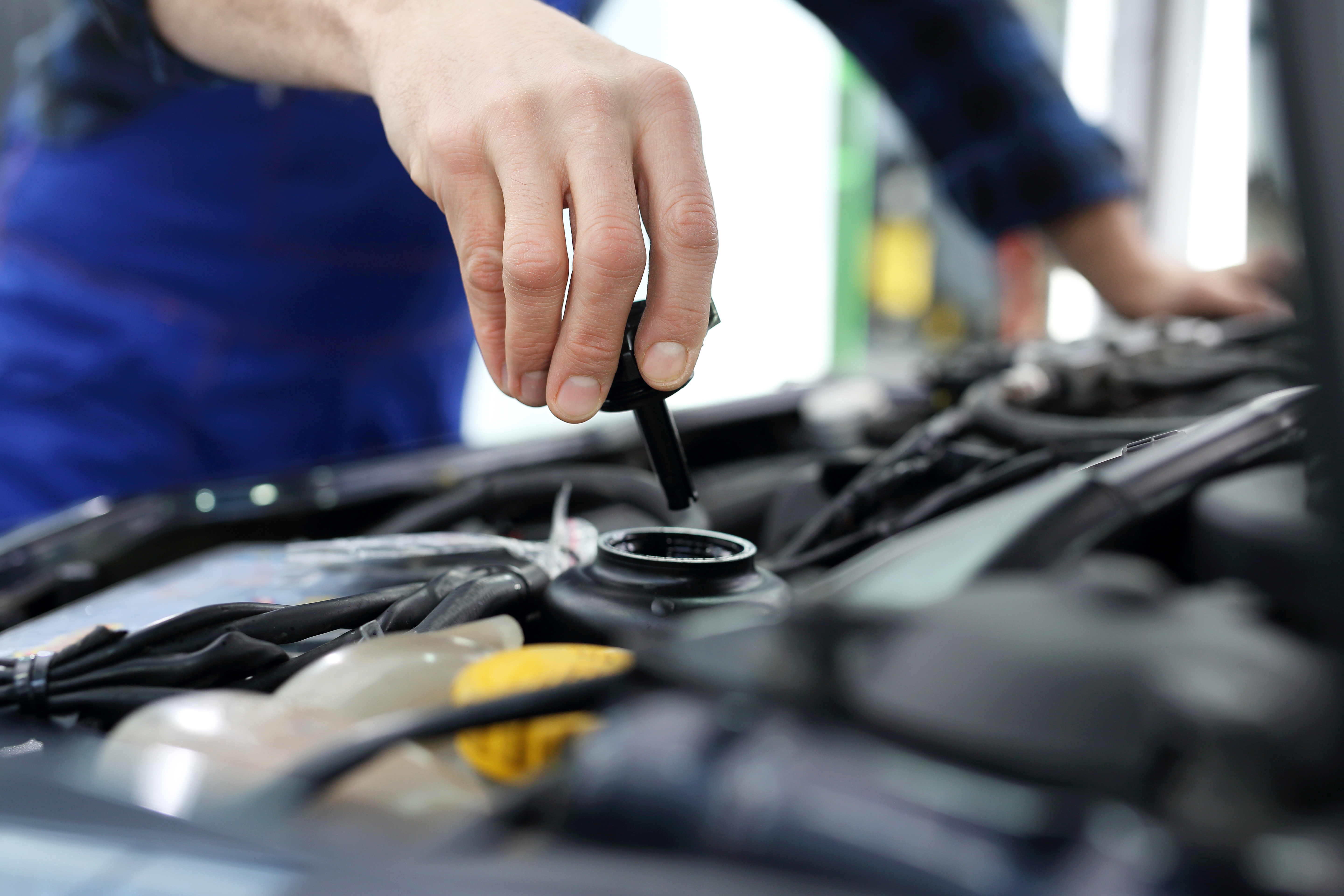 mechanic puts cap back on the oil reservoir for a vehicle