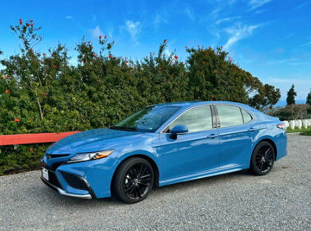 Blue Toyota Camry parked on a road on a sunny day.