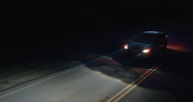 A Subaru driving at night with Advanced Headlights activated.