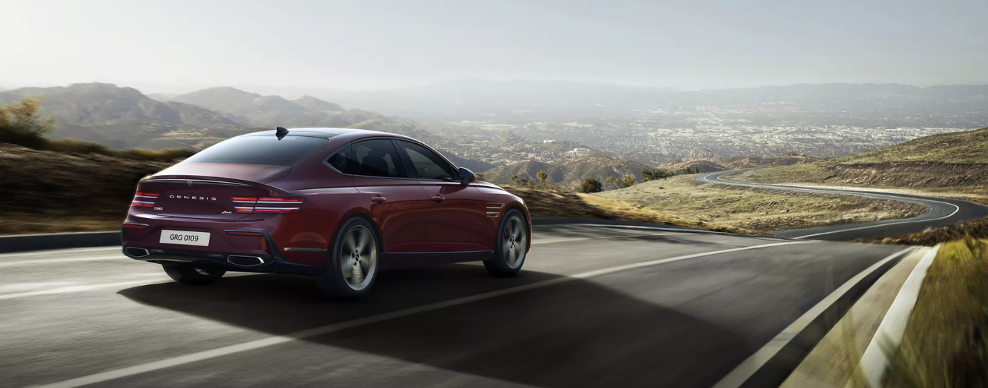 Red Genesis G80 driving on a winding road