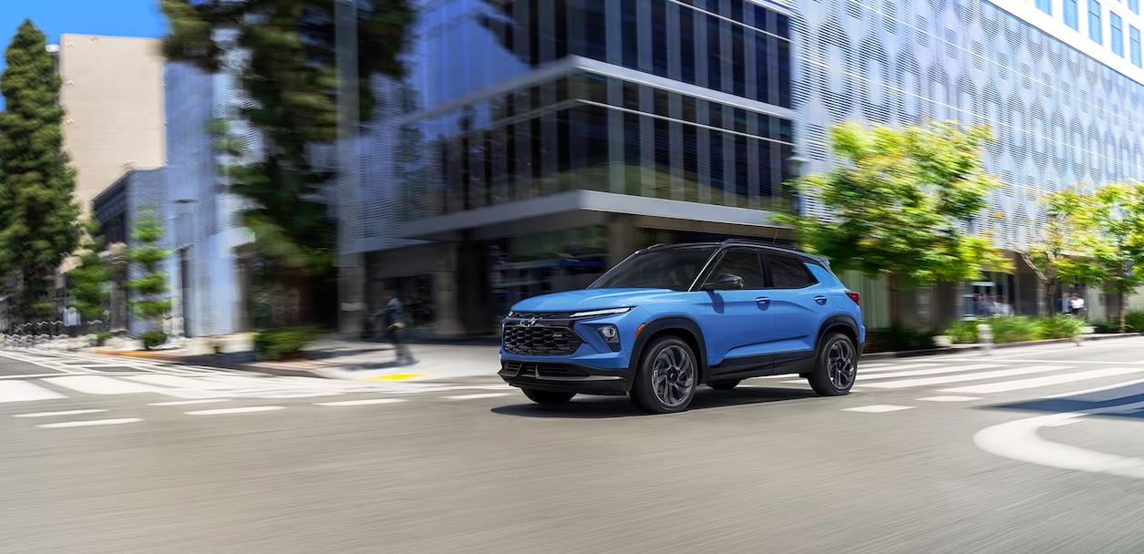 2024 Chevrolet Trailblazer in vibrant blue driving through a modern urban city, showcasing its sleek design and dynamic performance.