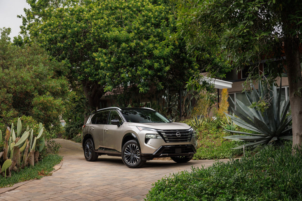 2024 Nissan Rogue in Baja Storm in front of a green scenery 