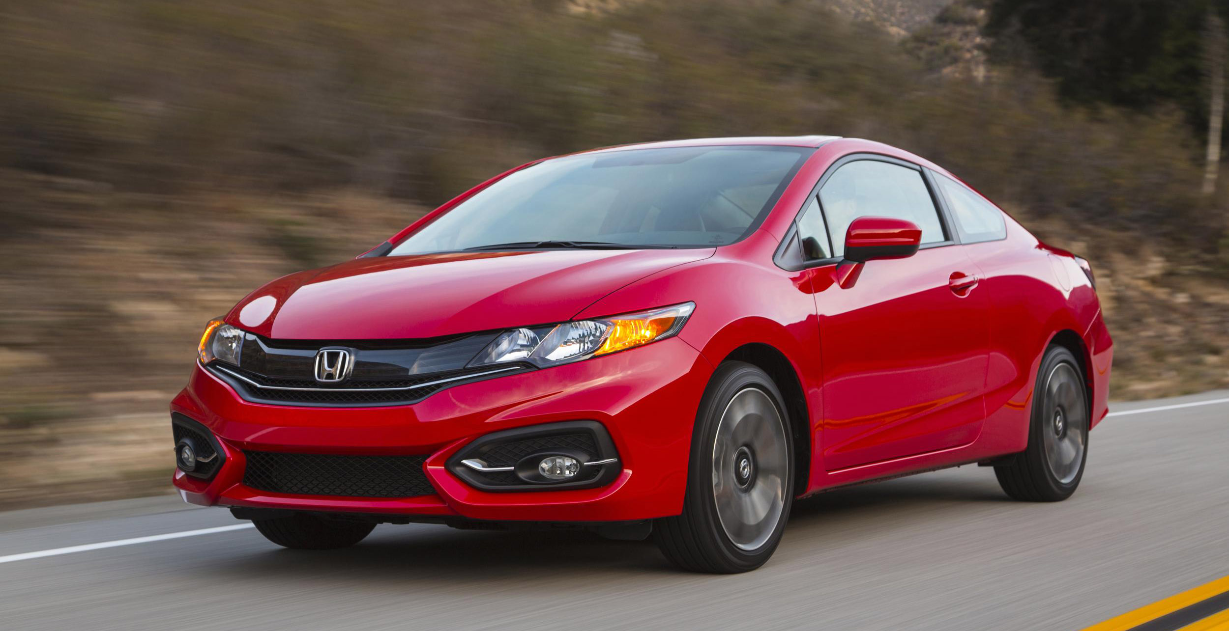 A red used Honda Civic drives down the road.