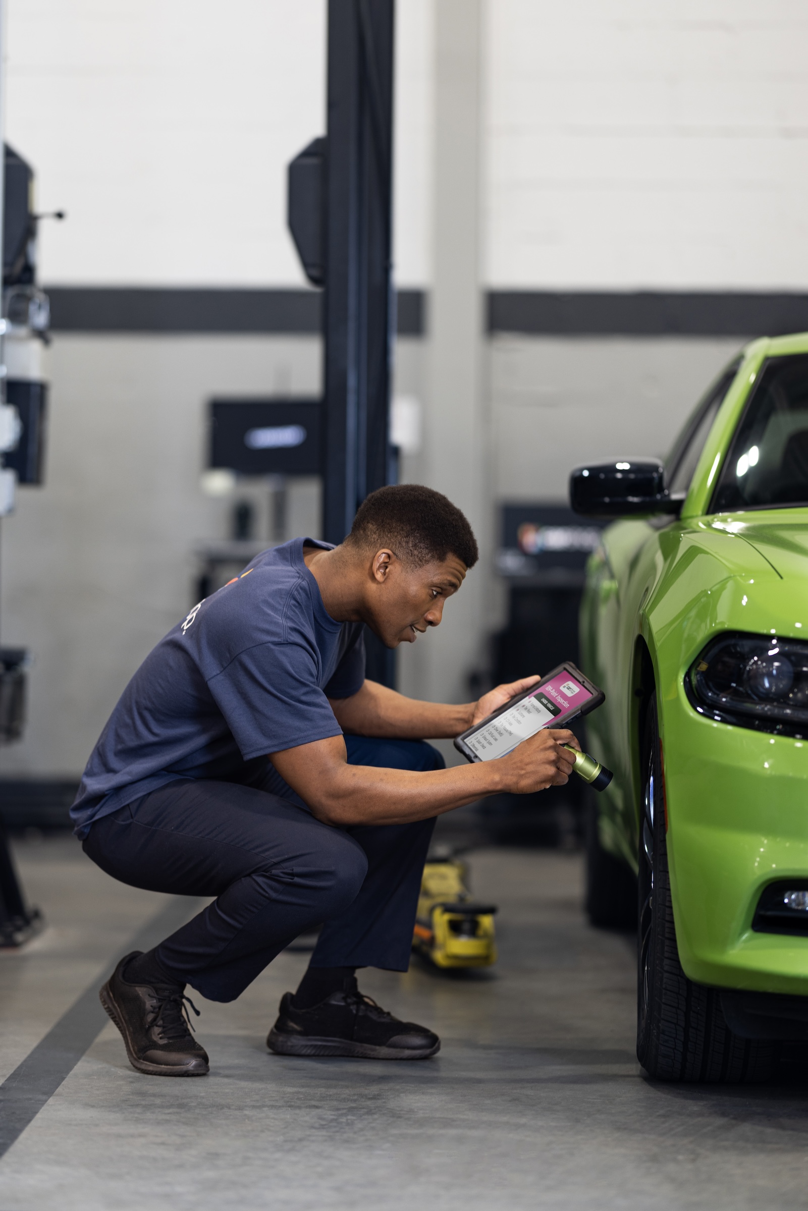 Associate examining car tire with flashlight