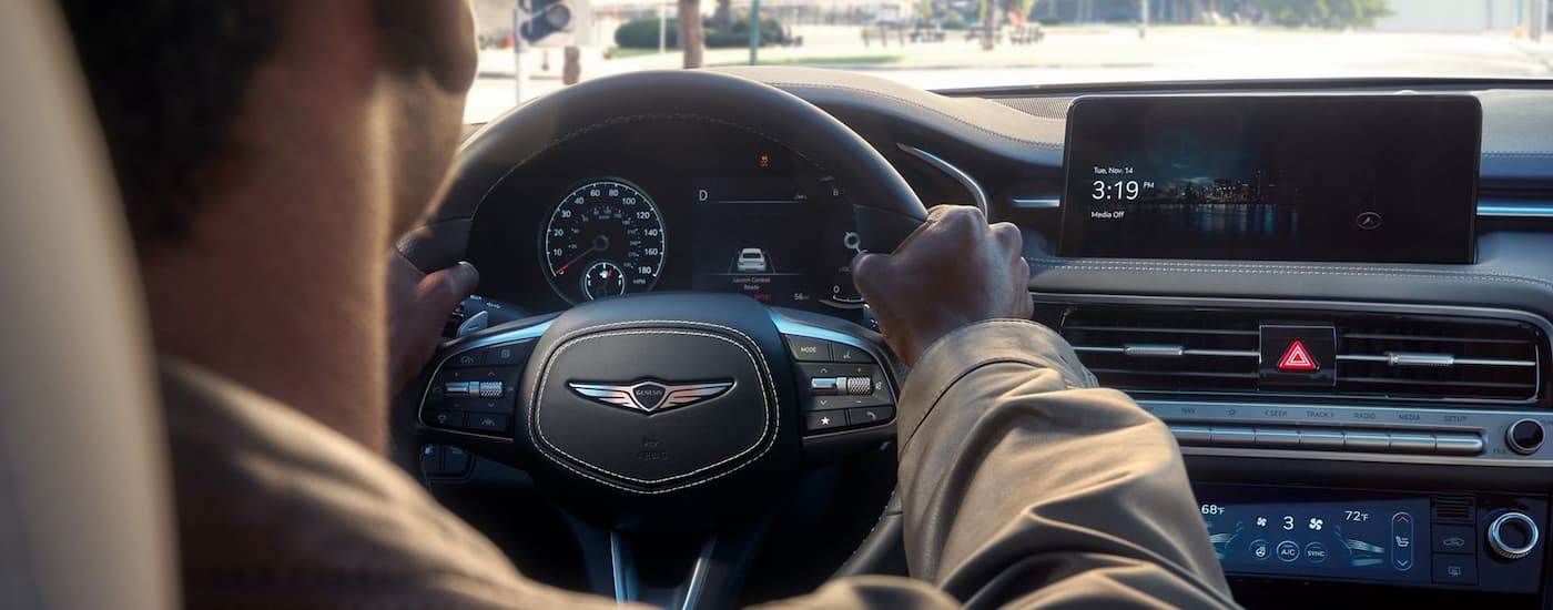 A man driving in a 2026 Genesis G70