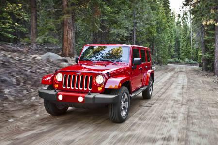 Red Jeep Wrangler Unlimited driving on a forest dirt trail