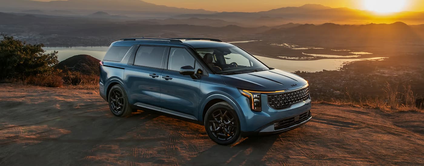 Blue 2026 Kia Carnival parked overlooking a valley