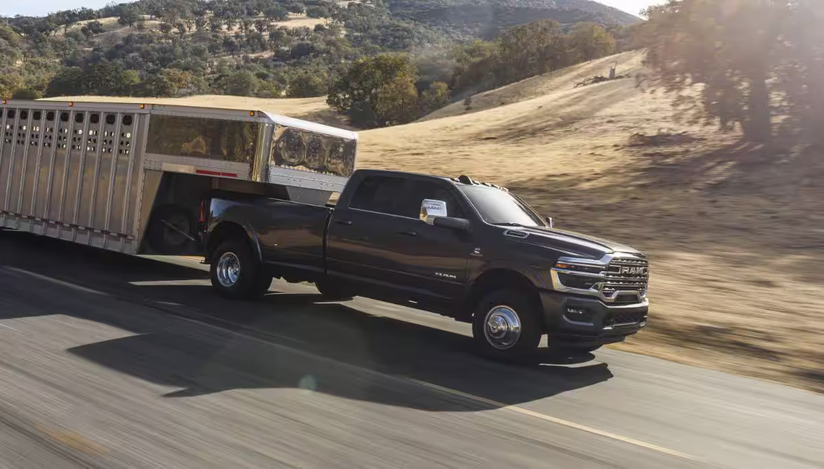 A gray truck pulling a trailer down the road.
