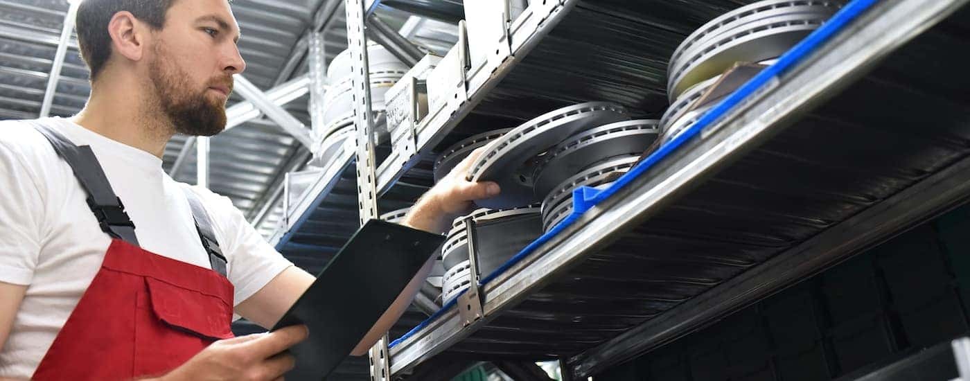 A mechanic is shown grabbing a rotor off a shelf.
