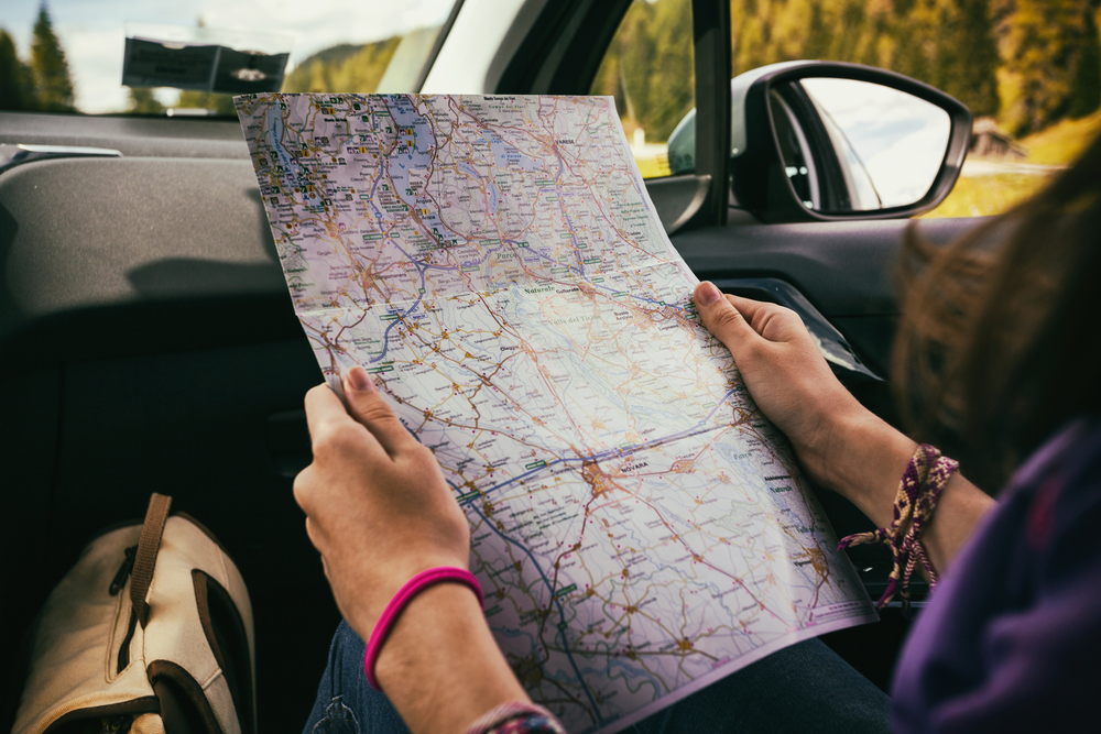 woman intensely studying a road map inside of a car