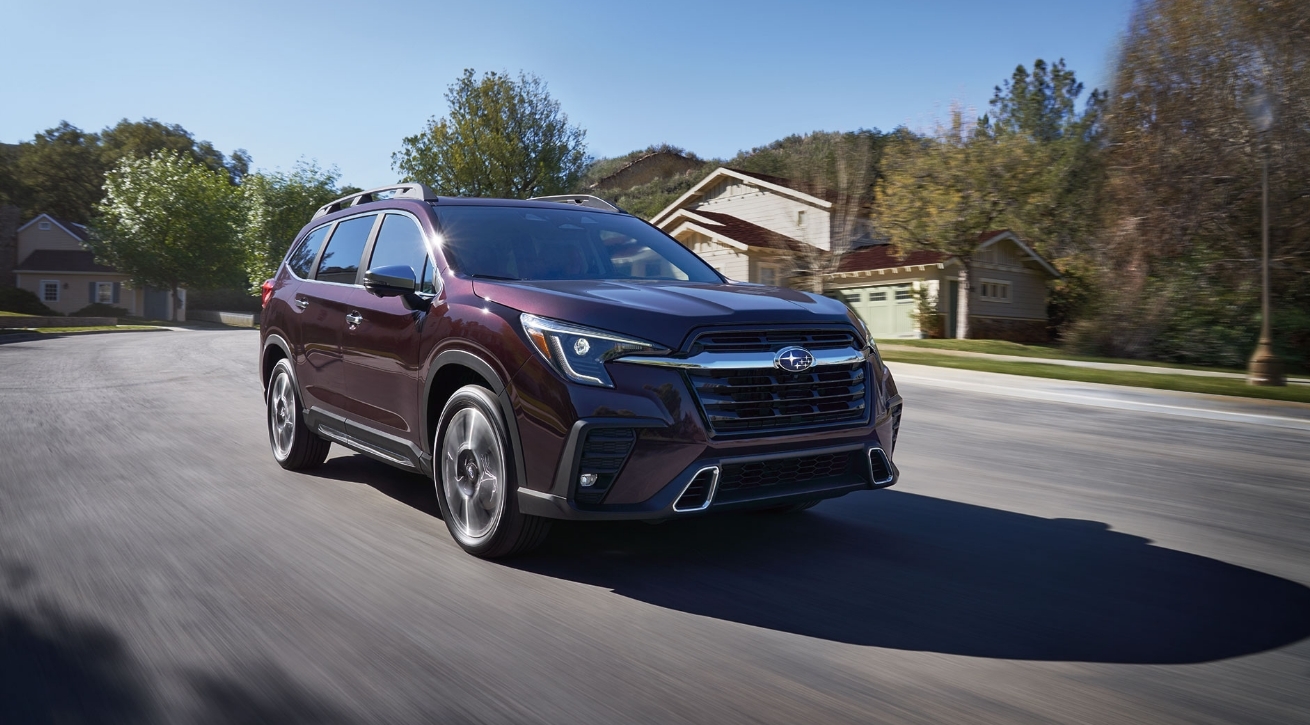 A dark red Subaru SUV driving through a neighborhood.