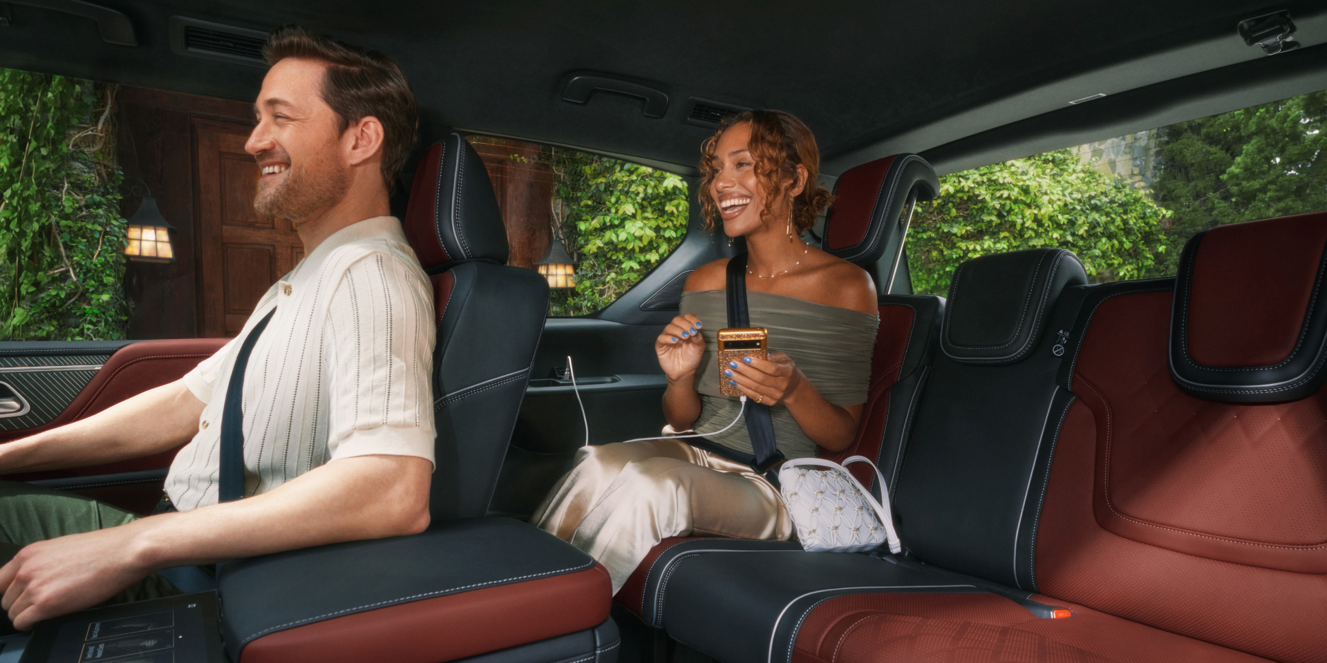 Second-row captain's chair in the 2027 INFINITI QX80 with a passenger using a smartphone connected to an integrated USB charging port, showing quilted leather seating.