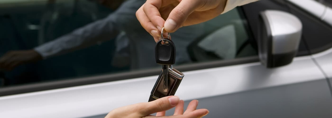 salesman passing over new car key