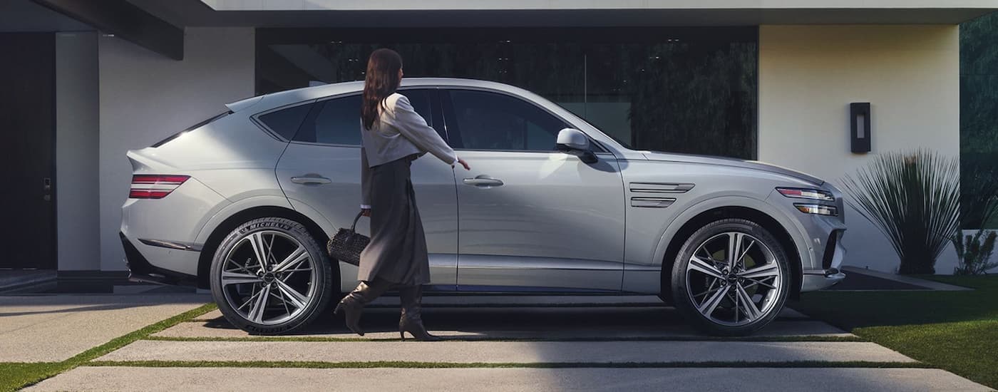 Woman walking towards passenger door on a silver 2026 Genesis GV80 Coupe
